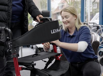 Eine Mitarbeiterin hilft einem älterem Herren bei der Einrichtung eines Rollstuhls im Rahmen der Reha-Technik Beratung