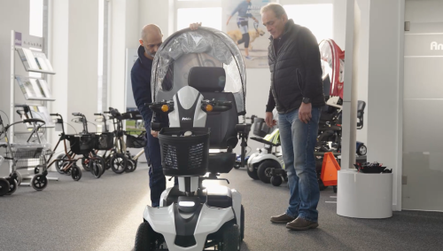 2 Mitarbeiter bauen die "Cappi-Erweiterung" (Wetterverdeck) an ein Elektromobil